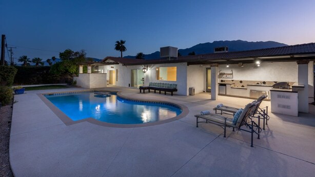 Un jardin à l’arrière d’une maison, avec une piscine, un espace salon extérieur et un coin barbecue.