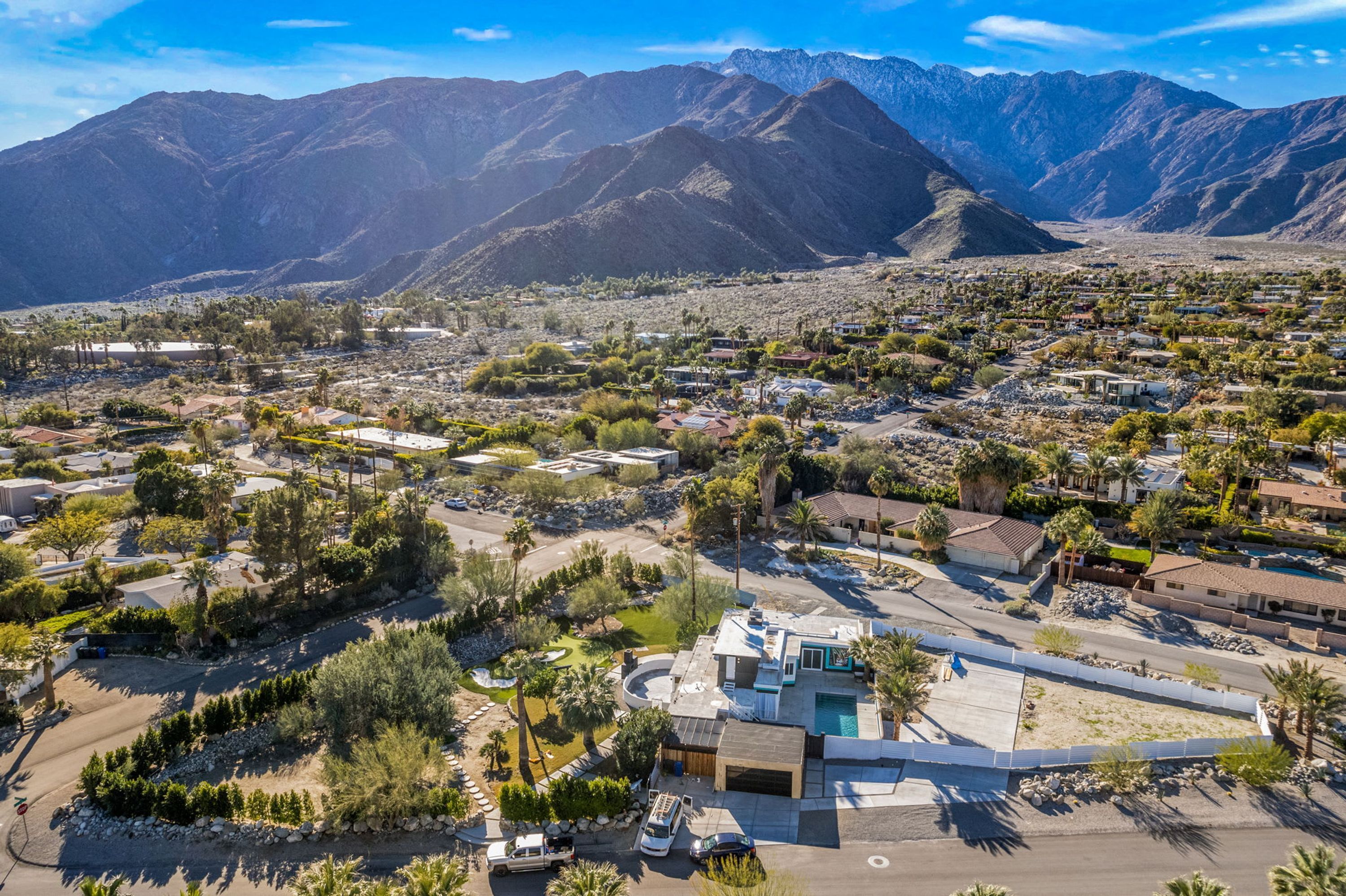 An aerial view of a residential area with houses, roads, and mountains in the background.