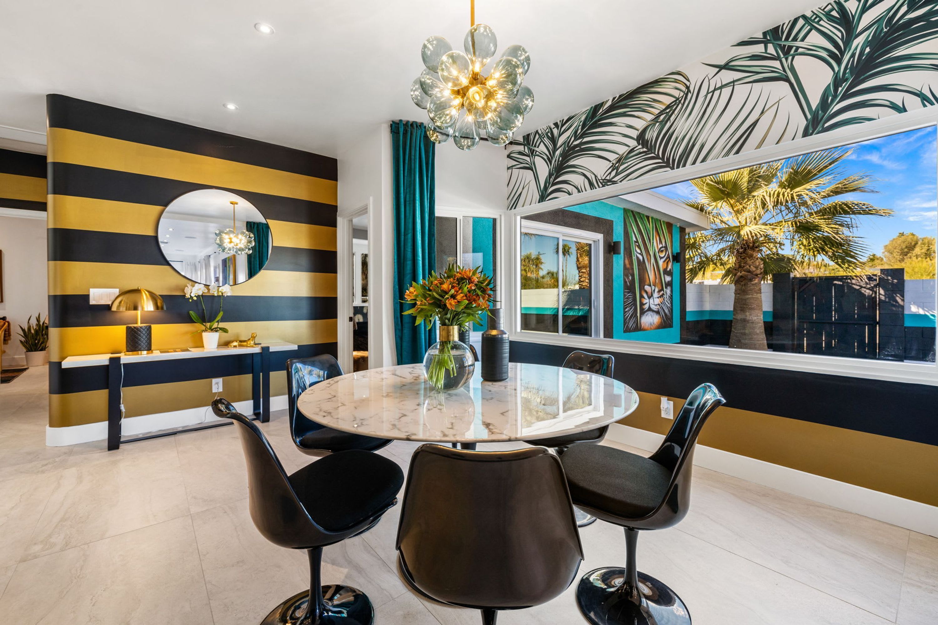 A modern dining area with a round table, black chairs, and a decorative mirror.