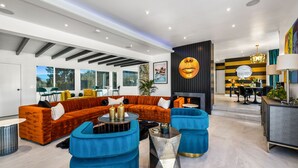 A modern living room with a sectional sofa, blue ottomans, and a fireplace. - The Escape Island (Palm Springs)