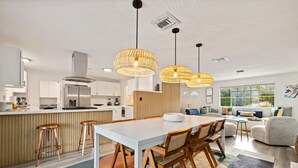 A modern kitchen with a central island, bar stools, and pendant lighting. - The Fig Ranch (Palm Springs)