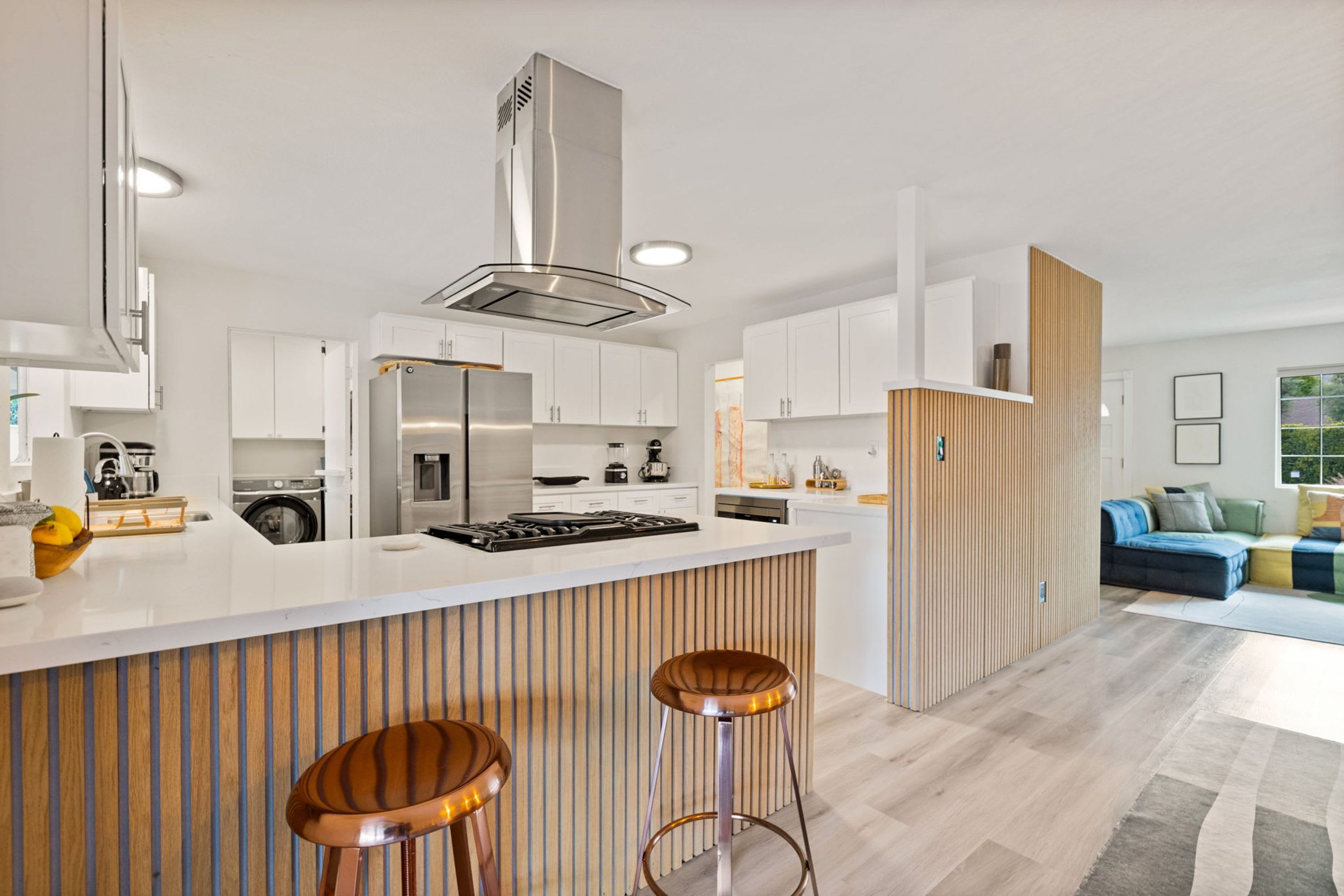 A modern kitchen with white cabinets, stainless steel appliances, and a central island with stools.