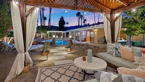 An outdoor patio area with a pool, seating, and a covered section with a pergola. - The Fig Ranch (Palm Springs)