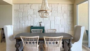 Un coin repas agrémenté d’un mur en pierre, d’un lustre et de chaises en osier.