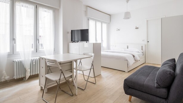 A modern, minimalist bedroom with a bed, bedside table, and a TV. - Al Mercato Delle Erbe by Wonderful Italy (Bologna)