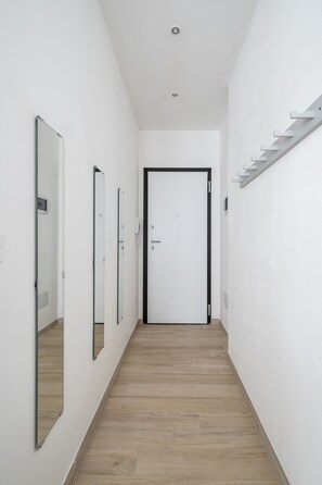 A hallway with a wooden floor, white walls, and a door at the end.