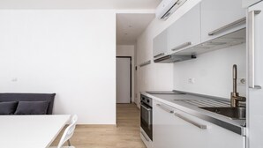 A modern kitchen with white cabinetry, stainless steel appliances, and a wooden floor. - Al Mercato Delle Erbe by Wonderful Italy (Bologna)