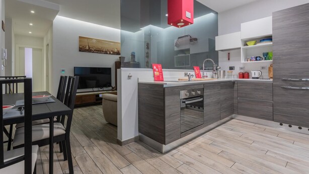 A modern kitchen with a central island, built-in oven, and a red accent light. - Graglia Modern Apartment by Wonderful Italy (Turin)