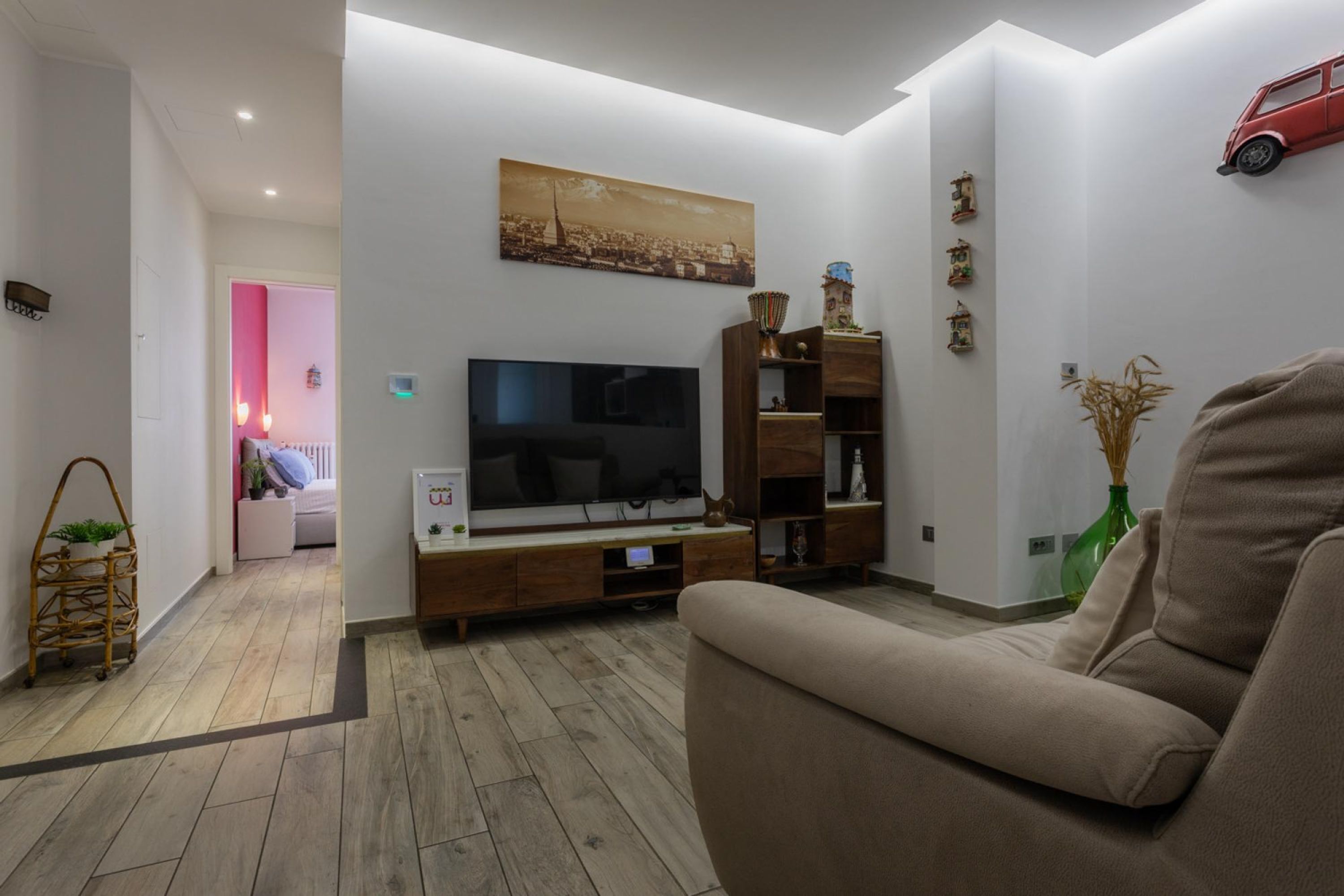 En moderne stue med et fladskærms-tv, et tv-møbel i træ og en beige sofa.
