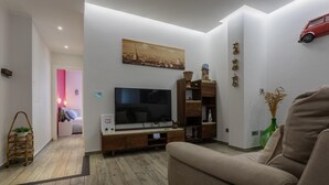 A modern living room with a flat-screen TV, wooden entertainment unit, and a beige sofa. - Graglia Modern Apartment by Wonderful Italy (Turin)