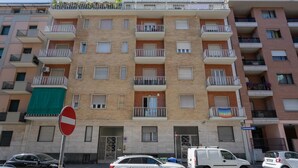 A multi-story residential building with balconies, a no entry sign, and parked cars. - Graglia Modern Apartment by Wonderful Italy (Turin)