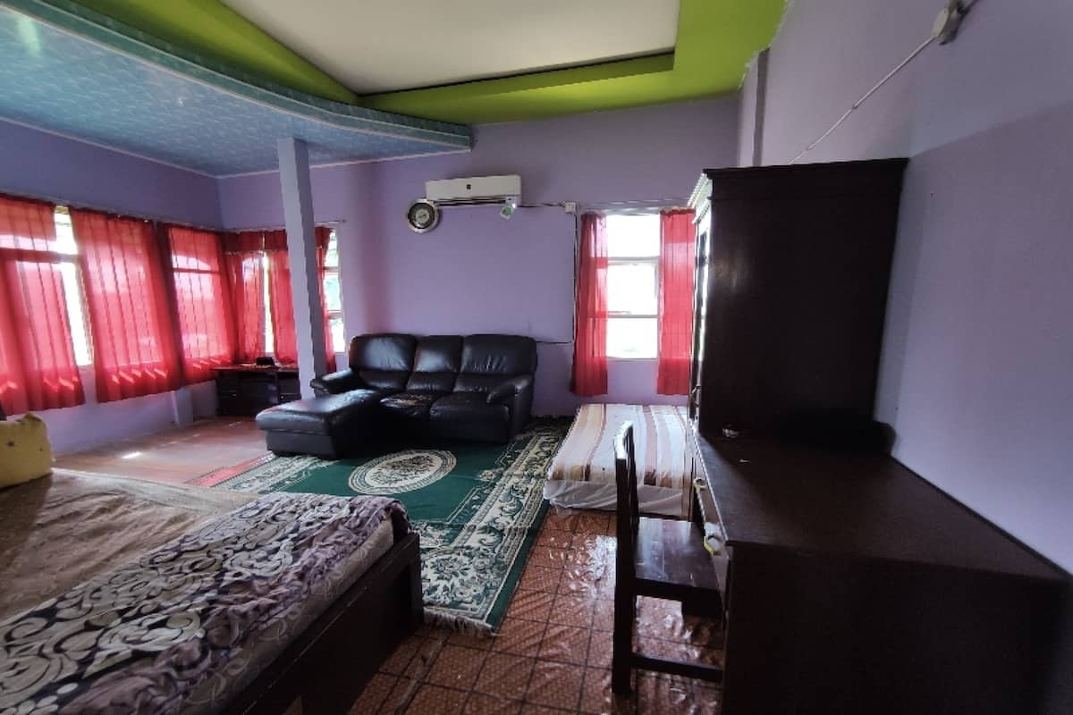 Ein Zimmer mit einem Bett, einem Sofa, einem Fernseher und einem Fenster mit roten Vorhängen.