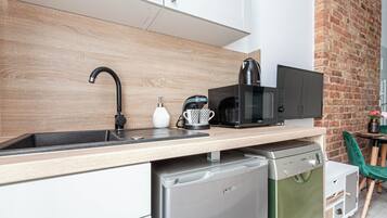 Una cocina moderna con salpicadero de madera, un microondas negro, una cafetera y un lavavajillas.