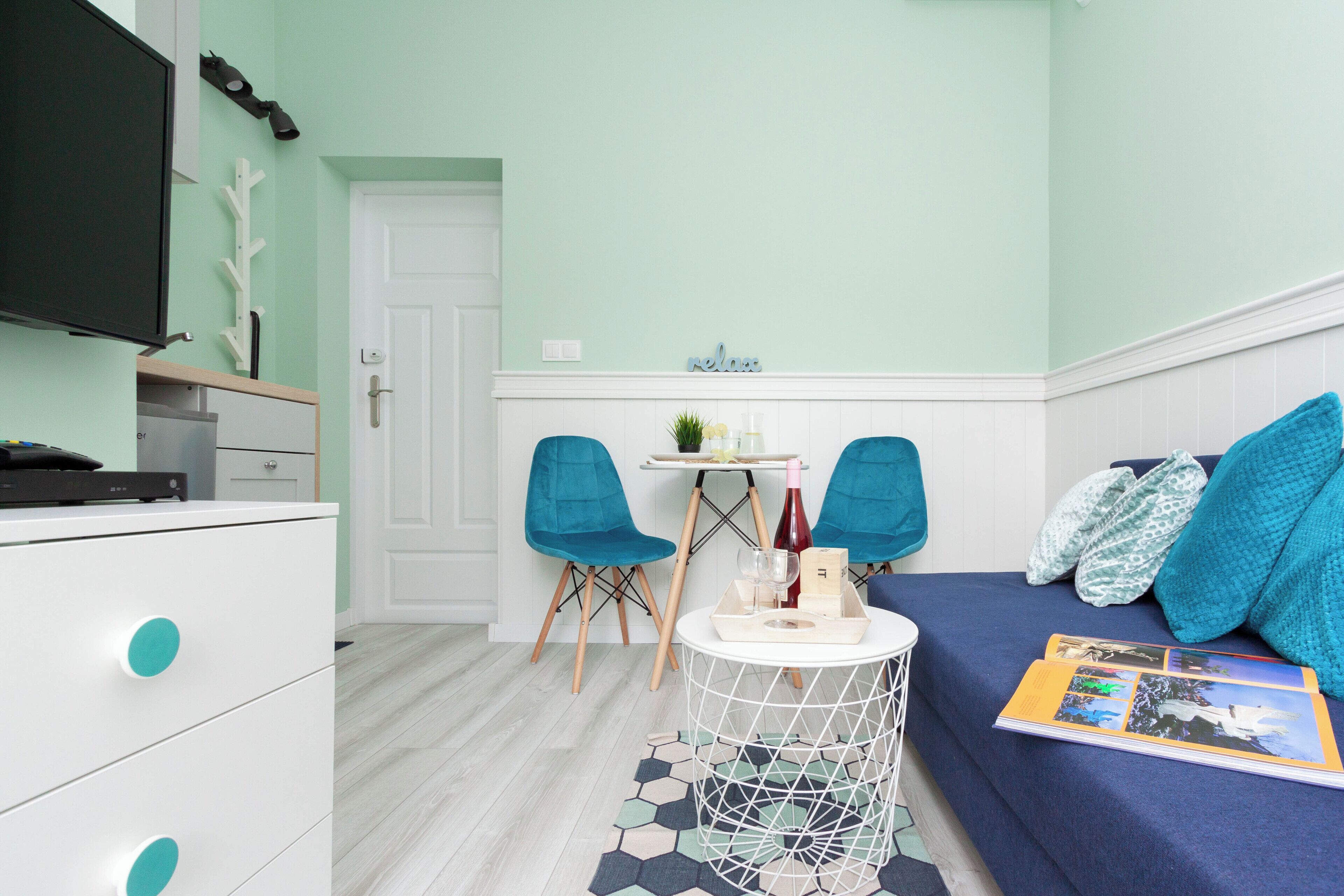 A compact room with a bed, a small round table, two chairs, a TV, and a dresser.