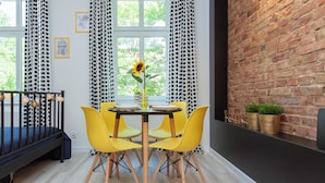 Un comedor con una mesa redonda, sillas amarillas, un jarrón con un girasol y una pared de ladrillo.