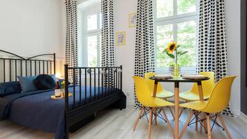 Un dormitorio con una cama, una mesa de comedor con sillas y una ventana con cortinas.