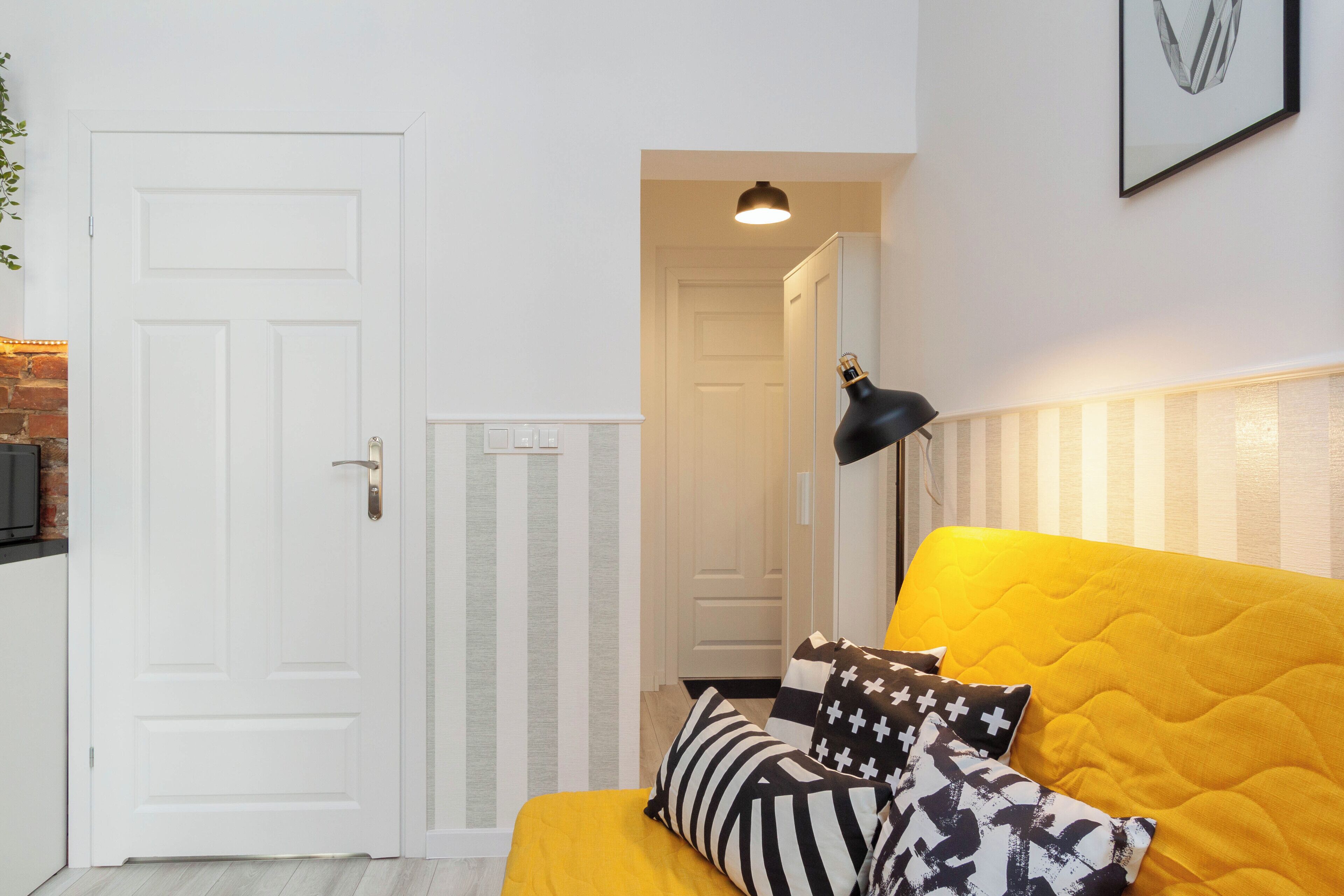 A room with a yellow bed, white walls, a white door, and a black lamp.