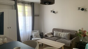 A modern living room with a sofa, a dining table, and a TV.