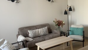 A modern living room with a grey sofa, a wooden coffee table, and a black floor lamp.
