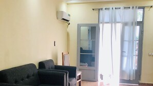 A living room with a sofa set, a coffee table, and a door with a curtain.
