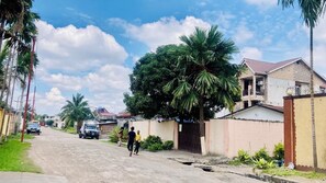 A residential street with houses, palm trees, and a clear sky. - Charmant Appartement 2 Chambres (Kinshasa)