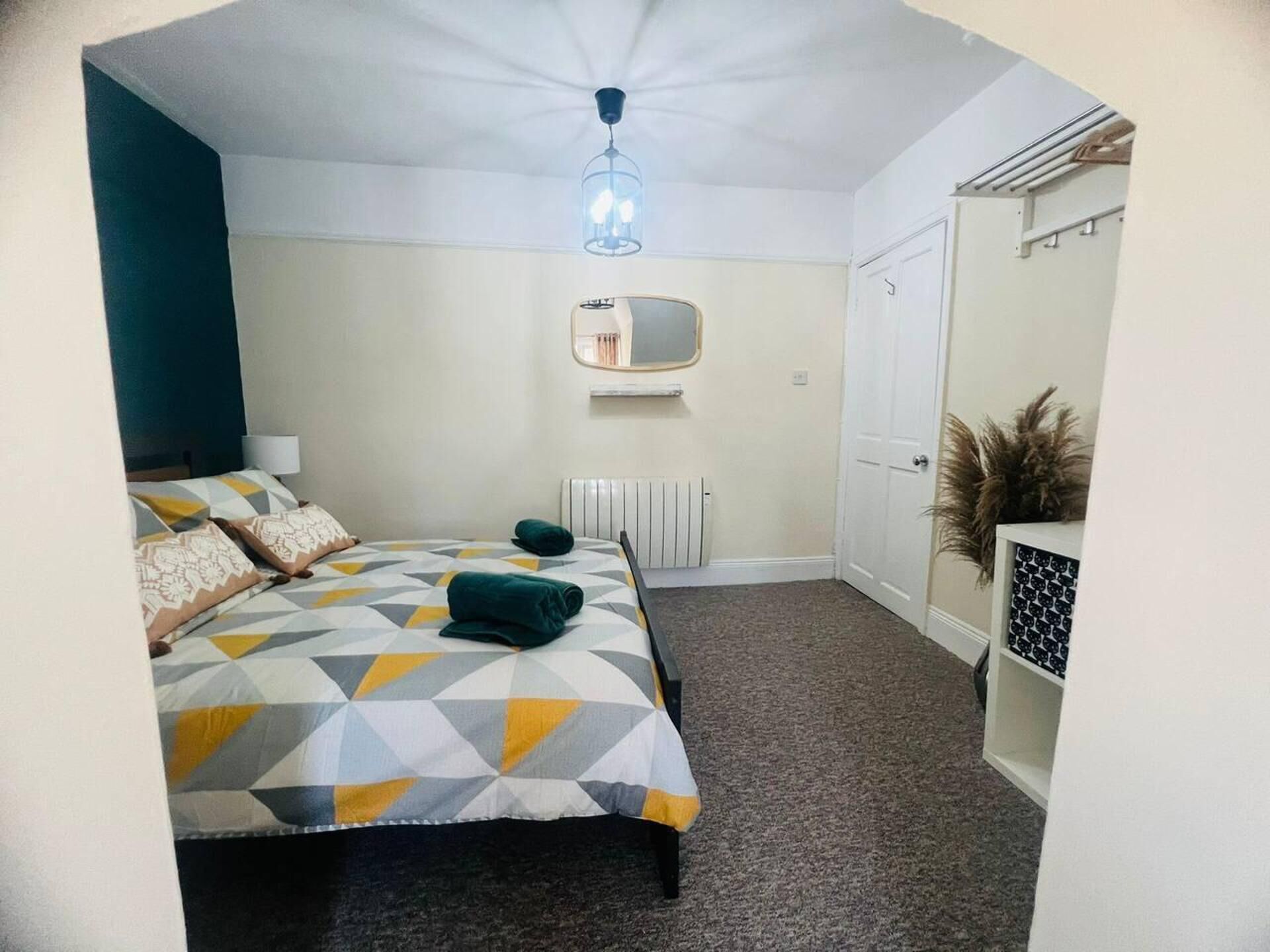 A bedroom with a bed, a radiator, a mirror, and a door.