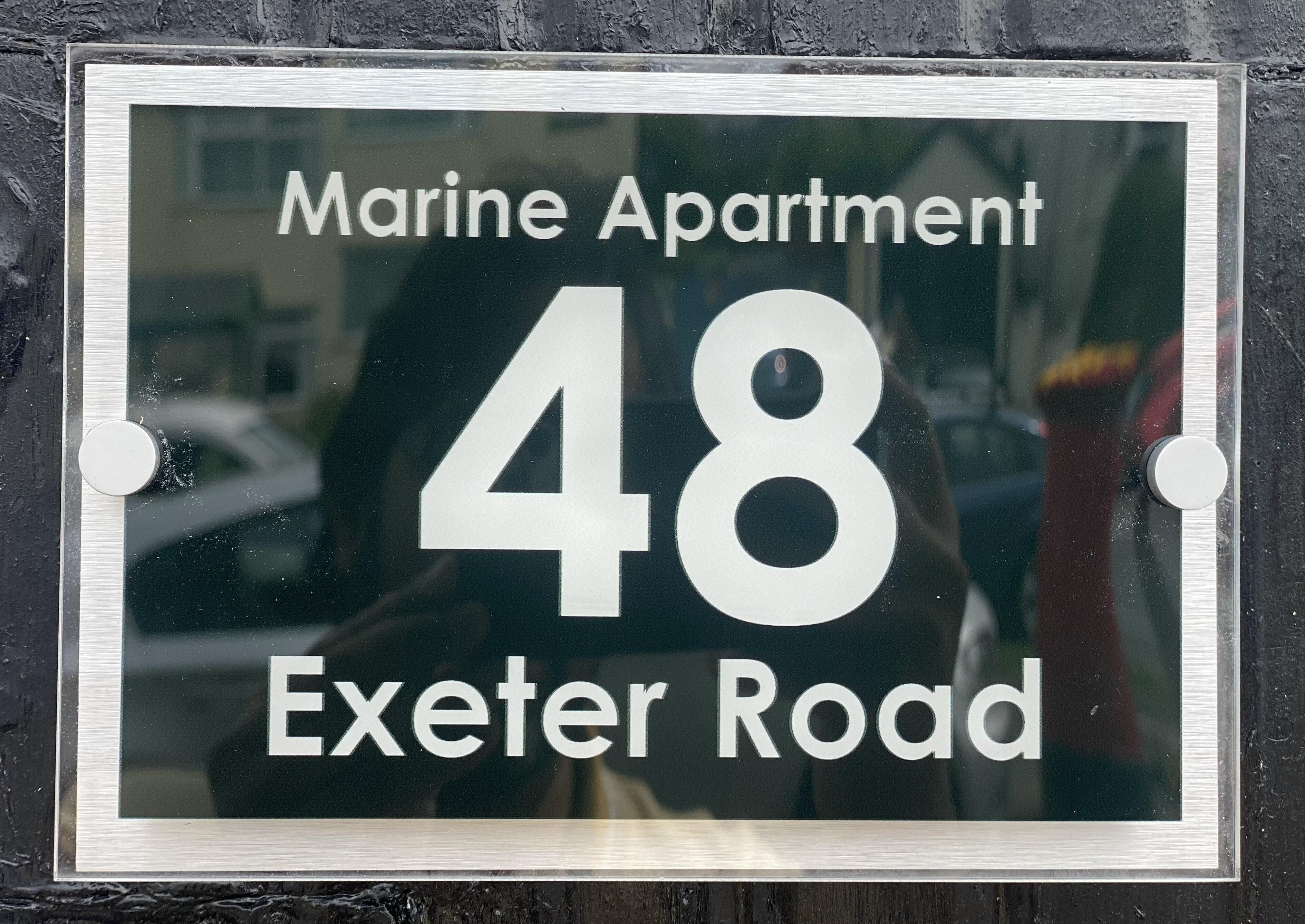 Placa indicando Apartamento Marine, número 48 na Exeter Road.