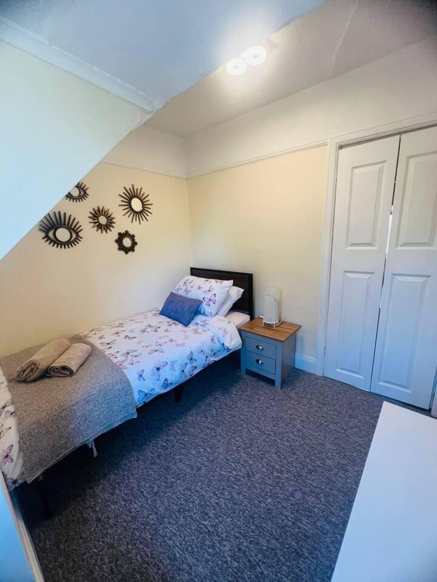 Una camera da letto con un letto, un comodino, una sveglia a parete e un armadio.