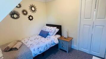 Una camera da letto con un letto, un comodino, una sveglia a parete e un armadio.