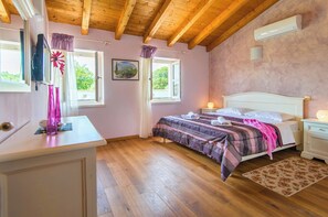 A bedroom with a wooden ceiling, a bed with a pink blanket, a nightstand with a lamp, and a window with curtains. - Beautiful 4 bedroom villa on peaceful location in village Pavićini (Šegotići)