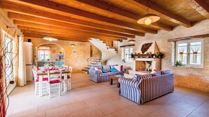 A spacious living area with wooden beams, a fireplace, striped sofas, and a dining table set for four. - Beautiful 4 bedroom villa on peaceful location in village Pavićini (Šegotići)