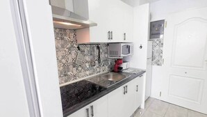 A kitchen with white cabinets, a black countertop, and patterned backsplash tiles. - Sea View Studio 2 in San Agustin (Maspalomas)