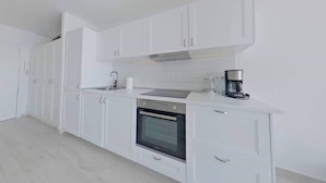 A modern kitchen with white cabinetry, a built-in oven, and a coffee maker. - Sea View Studio 1 in San Agustin (San Agustin)