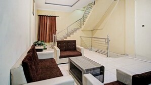 A modern living room with a sofa set, a coffee table, and a staircase leading to an upper floor. - OYO 90381 Belva Guest House (Medan)