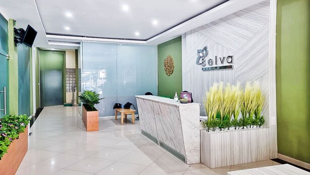 A reception area with a marble counter, a green wall, and a sign that reads "Belva". - OYO 90381 Belva Guest House (Medan)