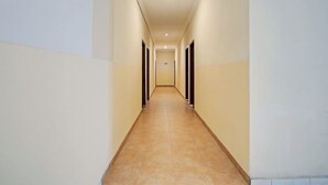 A long, narrow hallway with beige walls and a tiled floor, leading to multiple doors. - OYO 90381 Belva Guest House (Medan)