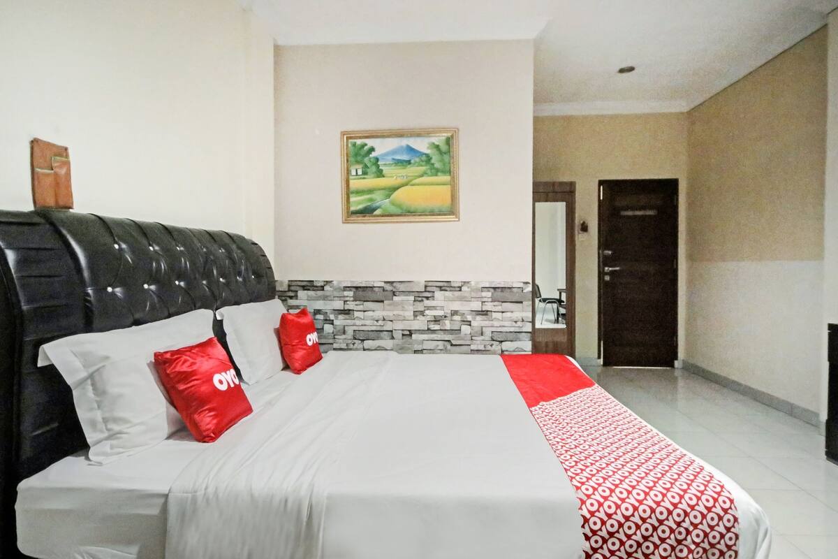 Una habitación de hotel con una cama, una pared de piedra, un cuadro y una puerta.
