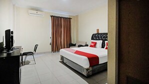 A hotel room with a bed, a desk, a chair, and an air conditioning unit. - OYO 90381 Belva Guest House (Medan)
