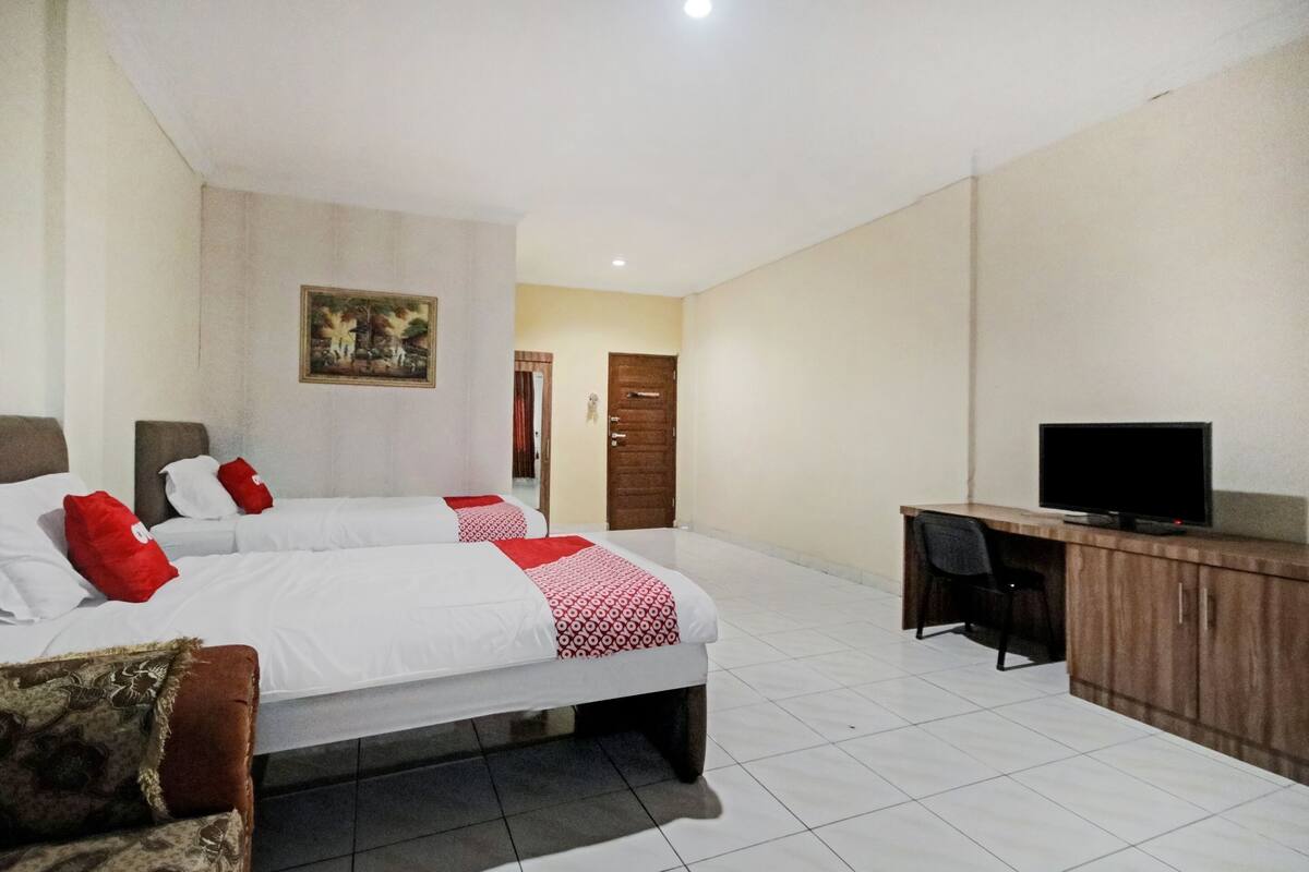 Una habitación de hotel con dos camas, un escritorio, un televisor y una puerta.