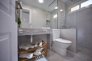 Ein modernes Badezimmer mit Toilette, Waschbecken und Dusche. Ein Handtuchhalter mit Handtüchern und ein Spiegel über dem Waschbecken.