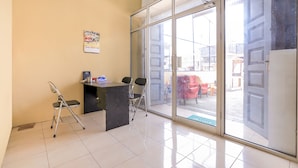 Une chambre moderne avec une porte vitr ée donnant sur l’extérieur, un bureau avec deux chaises et une petite planche à repasser.