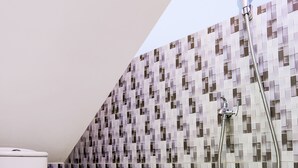 Une salle de bain avec des toilettes, une douche et un mur carrelé.