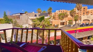 A balcony with a hammock and a view of buildings and palm trees. - Cabo Tortuga Hotel Boutique (Cabo San Lucas)