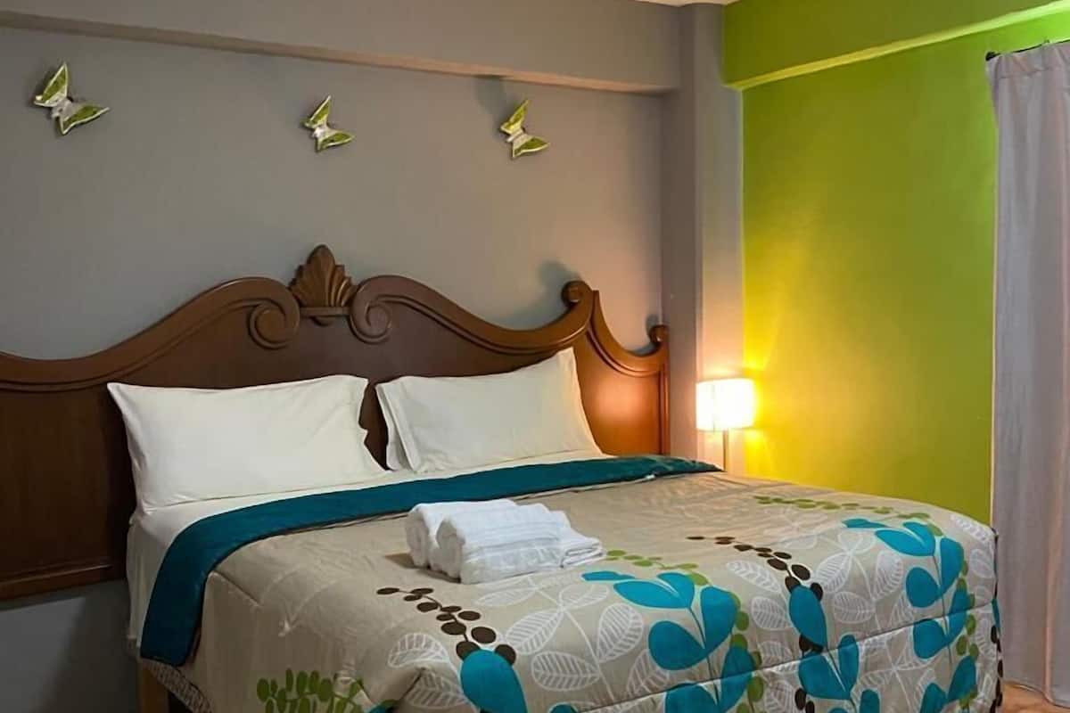 A neatly made bed with a floral bedspread, a wooden headboard, and decorative wall art.