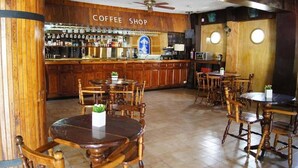 A coffee shop with wooden furniture and a bar area. - Cabo Tortuga Hotel Boutique (Cabo San Lucas)