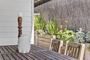 Uma mesa de madeira com um vaso branco e um castiçal, rodeada por cadeiras de madeira.
