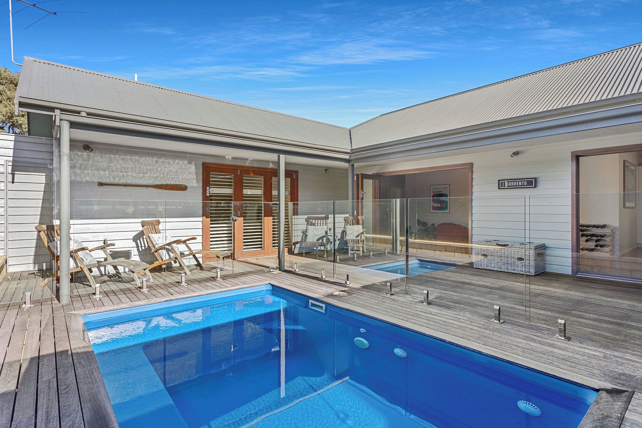 A modern house with a swimming pool, wooden deck, and lounge chairs.