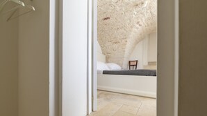 Une chambre avec un plafond en pierre, un lit avec une literie blanche et une chaise.