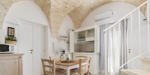 A kitchen with white cabinets, a dining table with chairs, and a staircase.