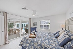 A bedroom with a large bed, a ceiling fan, a window with blinds, and a view of the outside. - Direct Boating Access | Olde Marco Home w/ Pool (Marco Island)